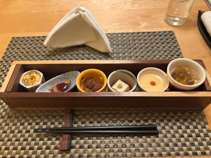 テーブルに置かれた前菜6種類。他に箸とナプキンが置いてある。