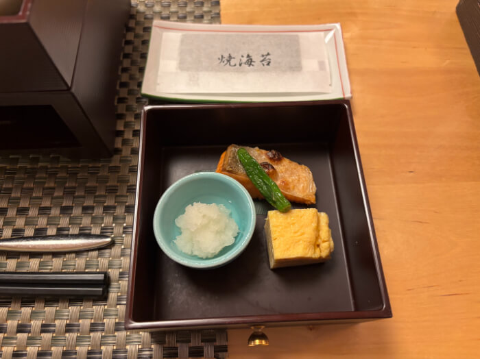 重箱の下段には銀鮭とだし巻き卵、小鉢に入った大根おろしがある。袋に入った焼海苔が小皿にのっている。