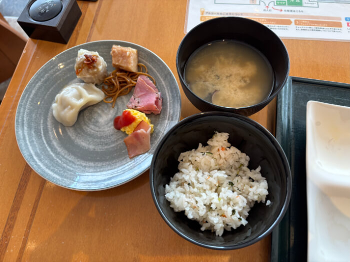 しじみのみそ汁と混ぜご飯。取ってきた料理はシュウマイ、水餃子、スクランブルエッグ、ベーコンなど。